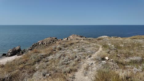 A-scenic-view-of-a-beach-in-Crimea,-Russia-with-a-path-leading-down-to-the-sandy-shoreline-and-clear-blue-water-beyond