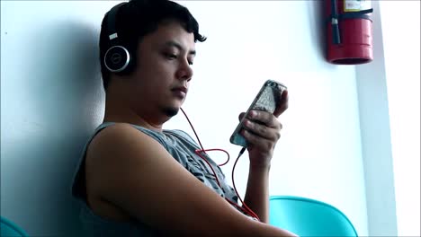 ANTIPOLO-CITY,-PHILIPPINES-–-JULY-12,-2019:-An-adult-Filipino-man-uses-a-smartphone-while-sitting-on-a-bench-at-waiting-area