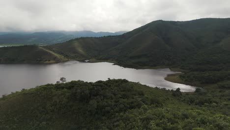 Drone-advancing-over-green-mountains-and-uncovering-Embalse-Campo-Alegre