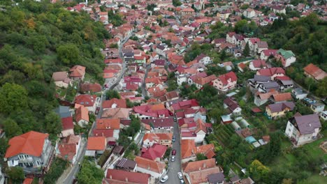 A-colorful-village-nestled-in-lush-green-hills-during-the-day,-aerial-view