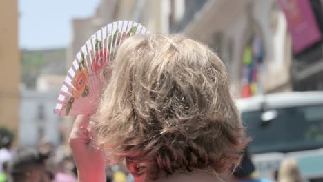 Close-up-of-a-blonde-woman-holding-a-fan-of-flowers-close-to-her-face-to-protect-herself-from-the-sun