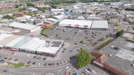 Drone-fly-in-of-the-Bridgwater-Retail-Park,-featuring-various-shops,-large-parking-lots,-and-surrounding-roads,-Bridgwater,-United-Kingdom,-July-2024