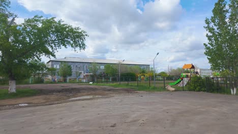 Blick-Auf-Einen-örtlichen-Spielplatz-Auf-Einem-Weitläufigen-Gelände-Mit-Einem-Gebäude-Im-Hintergrund-In-Kasachstan,-Zentralasien-–-Weitwinkelaufnahme