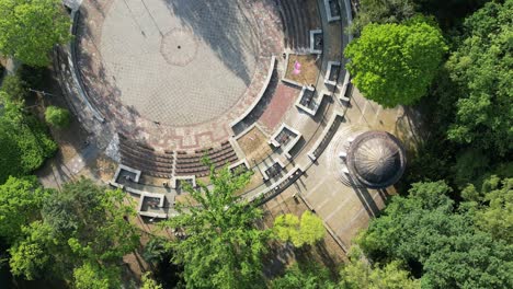 Dancing-circle-in-silesian-park-during-a-beautiful-summer-day-surrounded-by-lush-greenery-and-grass---drone-4K