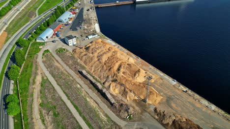 Aerial-view-of-a-construction-site-close-to-water,-going-forward