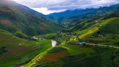 Vivid-green-rice-terraces-lit-by-early-morning-sun,-drone-hyper-lapse-through-valley