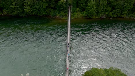 Aerial-top-down-flight-over-group-of-hiker-on-bridge-crossing-river-at-Kepler-Track,-New-Zealand