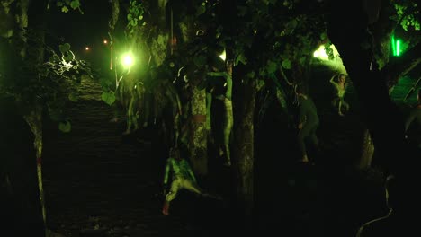 A-group-of-dancers-performing-ethnic-dances-in-the-dark,-surrounded-by-trees