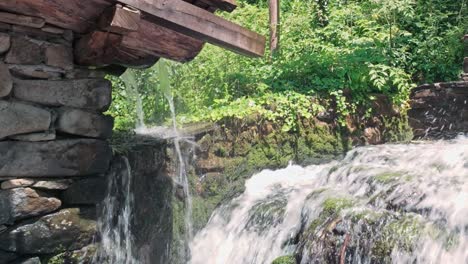 River-water-cascading-down-rocks-next-to-old-rustic-mill-setting