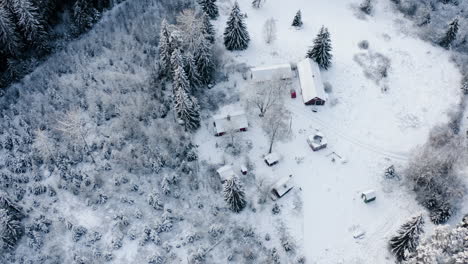 Luftaufnahme,-Umlaufbahn,-Drohnenschuss,-Rund-Um-Ein-Verschneites-Bauernhaus,-Mitten-In-Einem-Schneebedeckten-Wald,-An-Einem-Dunklen,-Bewölkten-Wintertag,-In-Lammi,-Kanta-Häme,-Finnland