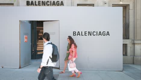 Pedestrians-walk-past-the-new-Spanish-luxury-fashion-brand-store,-Balenciaga,-currently-under-construction-in-Spain