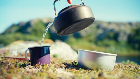 Gießen-Sie-Heißes-Wasser-Aus-Einem-Wasserkocher-Im-Freien-In-Eine-Tasse-Und-Einen-Topf