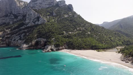 Ascenso-Aéreo-Cerca-De-La-Playa-De-La-Costa-Tropical-De-Baunei,-Con-Aguas-Turquesas,-Cerdeña