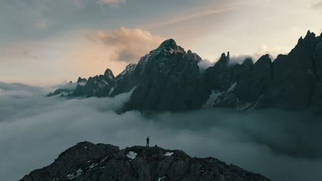 Alpine-valley-covered-with-a-layer-of-clouds-and-a-mountain-range-in-the-background-during-sunset