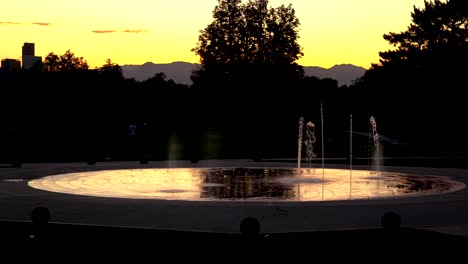 Fuente-De-Agua-Con-El-Horizonte-De-Denver-Al-Atardecer-Como-Fondo