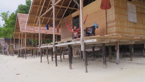 Woman-Relaxing-on-a-stilt-hut-veranda-on-Kri-Island,-Raja-Ampat,-Indonesia