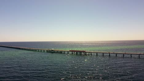 Vista-Aérea-Del-Embarcadero-De-Busselton-Con-Un-Tren-Circulando-Por-El-Embarcadero