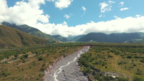 Panoramic-view-showing-a-nearly-dry-rocky-river-and-a-red-bridge-over-Route-9-in-the-background