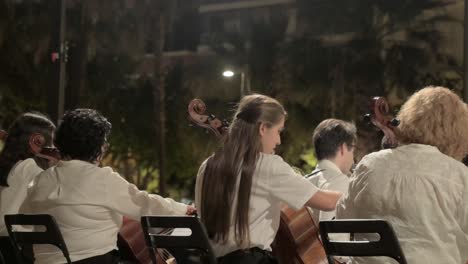 Brunette-girl-with-long-hair-playing-a-cello-in-a-brass-band-at-an-evening-performance-in-Sagunto