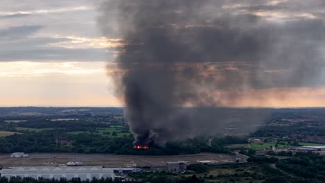 Blazing-derelict-building-fire-aerial-view-circling-ash-cloud-across-Cheshunt-skyline-in-the-distance