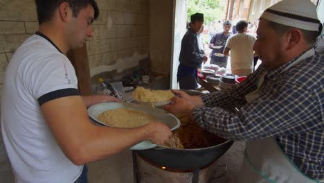 Local-Uzbek-preparing-Uzbek-pilav-or-plov,-a-national-dish-of-Uzbekistan-and-a-rice-dish-common-for-people-of-Central-Asia-in-Samarkand,-Uzbekistan