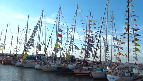 Video-displays-old-and-vintage-yachts-and-ships-that-have-masts-on-them-with-flags-on-top-of-them-waving-in-slow-motion-during-a-beautiful-summers-day-in-Europe-Baltics-Estonia-harbor-in-4K