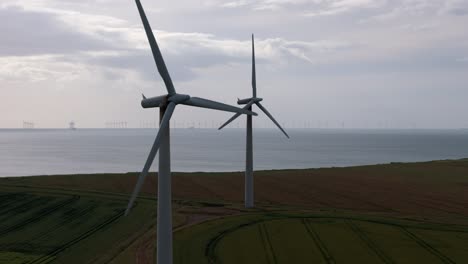 Drone-Aerial-footage-of-a-wind-turbine,-windmill-turning-in-the-wind-on-a-wind-farm-in-the-North-of-England-showing-renewable-energy-efficient-wind-power