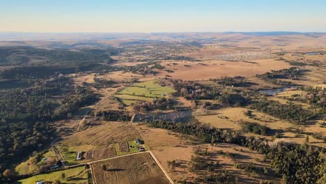 Picturesque-farming-community,-with-expansive-fields-and-a-distant-village-in-rural-South-Africa-from-a-drone's-bird's-eye-view