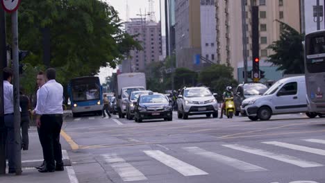 Ein-Zebrastreifen-Im-Zentrum-Von-Sao-Paulo,-Brasilien,-Während-Der-Hauptverkehrszeit,-Menschen-Gehen-Vorbei-Und-überqueren-Die-Straße