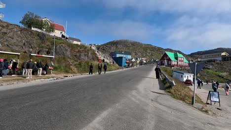 Tourists-walking-up-the-street-towards-the-hills-In-Qaqortoq,-Greenland