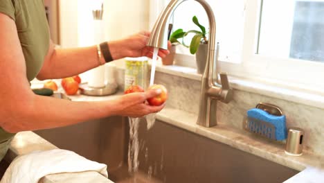 An-adult-woman-washing-apples-in-a-sink