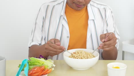 A-Young-Man-Sniffing-And-Stirring-Delicious-Boiled-Noodles-In-Bowl-With-Happy-Expression