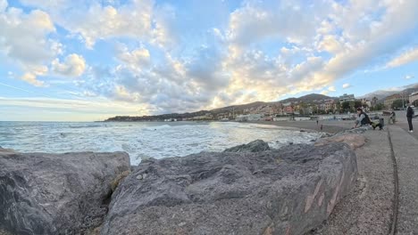 Time-lapse-of-people-visiting-the-beach-at-sunset-near-touristic-Italian-town