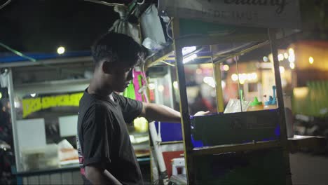 Joven-Indonesio-Cocinando-Comida-Callejera-En-El-Puesto-De-Su-Vendedor