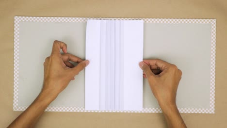 Hands-creating-a-hand-bound-book-with-precision,-showing-the-steps-involved-in-bookbinding