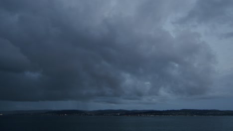 Timelapse-of-dark-clouds-rolling-in-over-a-lake,-with-rain-approaching,-a-dramatic-and-moody-atmosphere