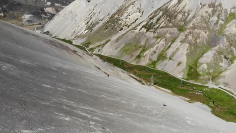 Two-mountain-bikers-speed-down-steep-scree-slope-in-remote-mountain-range-in-New-Zealand