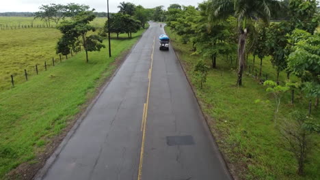 Coche-Circulando-Por-Una-Carretera-Tropical,-Con-Un-Barco-Encima