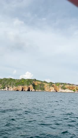 Marine-landscape-with-boat-going-to-distant-rocky-island-at-early-sunset-near-Phuket-in-Thailand