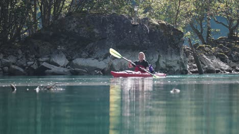 Alleinstehende-Kajakfahrerin-Paddelt-In-Der-Nähe-Der-Felsigen-Küste-Im-Naeroy-Fjord