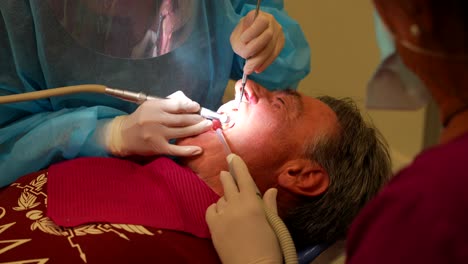 Dentist-using-dental-tools-to-remove-tartar-from-her-patient's-teeth