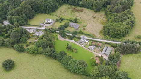 Aerial-of-an-abandoned-and-long-forgotten-empty-house-along-a-rural-road-amidst-a-green-countryside-landscape