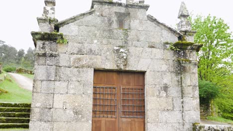 Stone-facade-of-the-San-Roque-Chapel-in-Beade,-Ourense,-Galicia,-Spain,-featuring-rustic-architecture-and-moss-covered-details