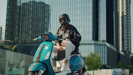 Junger-Rollerjunge-Sitzt-Auf-Seinem-Modernen-Elektromoped-Mit-Blick-Auf-Den-Skyline-Wolkenkratzer-Vor-Dem-Hintergrund-Einer-Intelligenten-Stadt