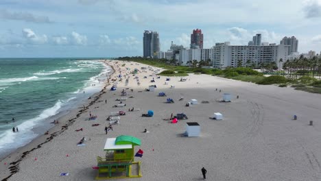 Vista-Aérea-De-South-Beach-Con-Bañistas-Y-Edificios-De-Gran-Altura