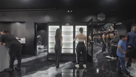 Two-fitness-enthusiasts-young-girls-selecting-their-favorite-energy-drink-and-expressing-satisfaction