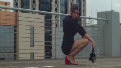 In-Port-of-Spain,-Trinidad,-a-young-girl-squats-on-a-rooftop-wearing-red-heels