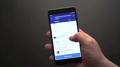 Nahaufnahme-Einer-Männlichen-Hand,-Die-Mit-Einem-Smartphone-Durch-Die-Bewertungen-Eines-New-Yorker-Hotels-Blättert
