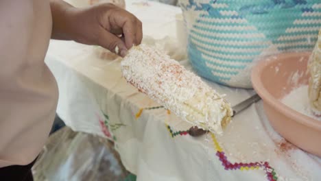 Close-up-of-person-adding-seasonings-to-traditional-corn-on-the-cob-dish