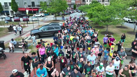 Aerial-flyover-crowd-of-runners-waving-into-camera